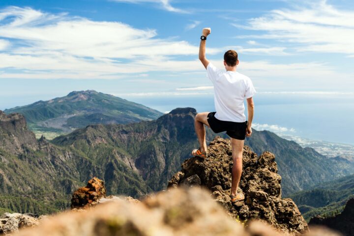 Man triumphantly at the top of a mountain